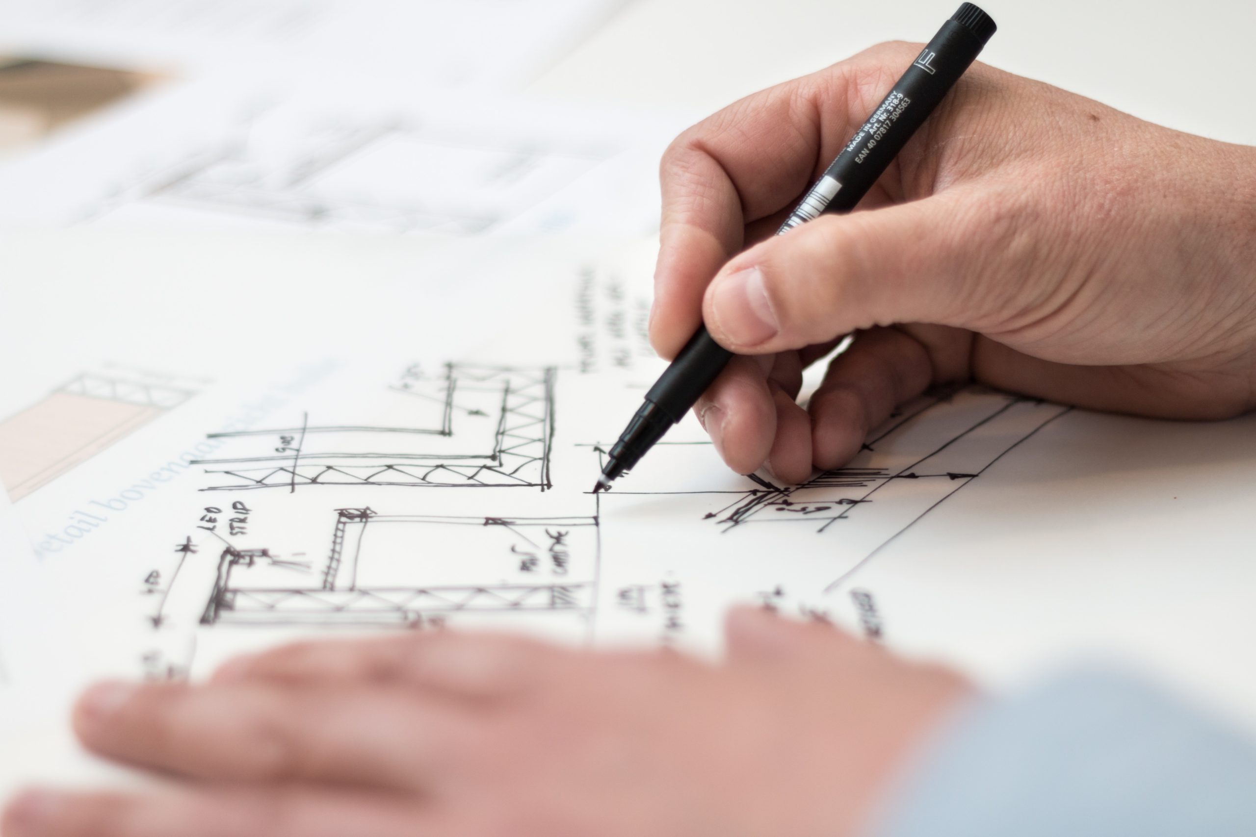 hand with pen over blueprint
